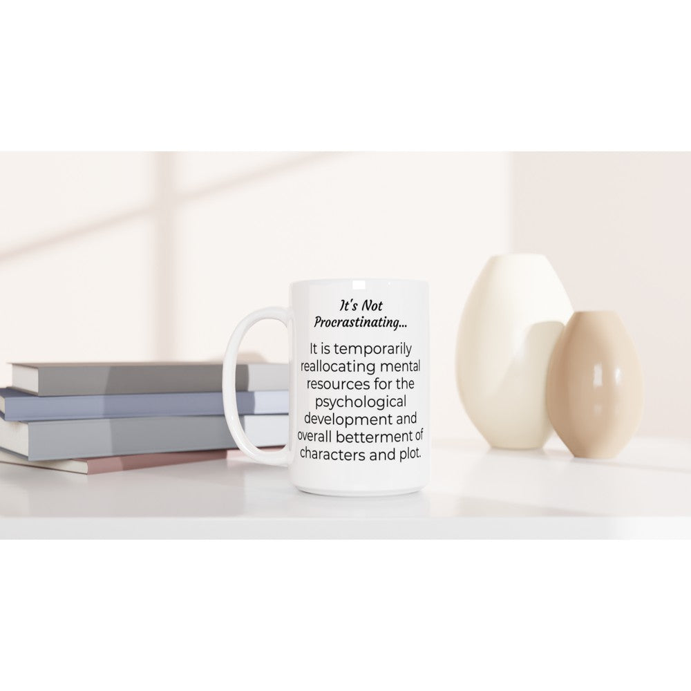 A white It's Not Procrastinating... // Writing Themed Mug with a quote on it, representing the writing process, sitting on a table.